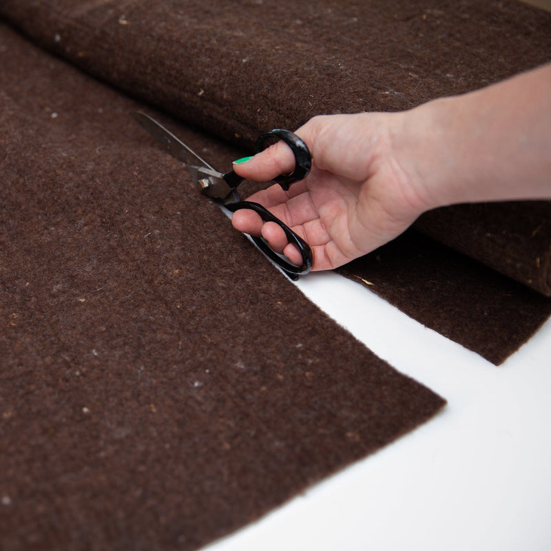 woldoek, een hand met schaar gaat door een bruine lap
