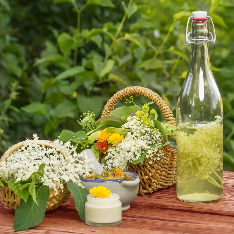 vlierbesbloesemlimonade, tafel met mandjes met vlierbloesem en een fles