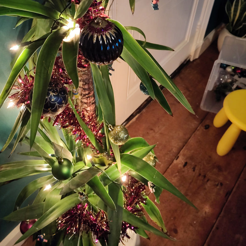 Palmlelie yucca met kerstverlichting kerstslingers en kerstballen