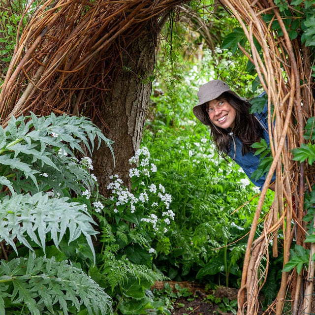 vrouw kijkt om hoekje wilde tuin
